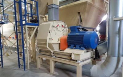 How do hammer mills contribute to reducing pellet and briquette production costs?